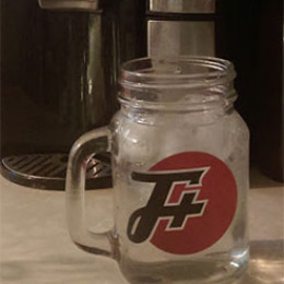 A clear mug filled with water with a transparent F Plus sticker on it.