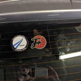 a prismatic F+ logo sticker next to a space sticker on a car